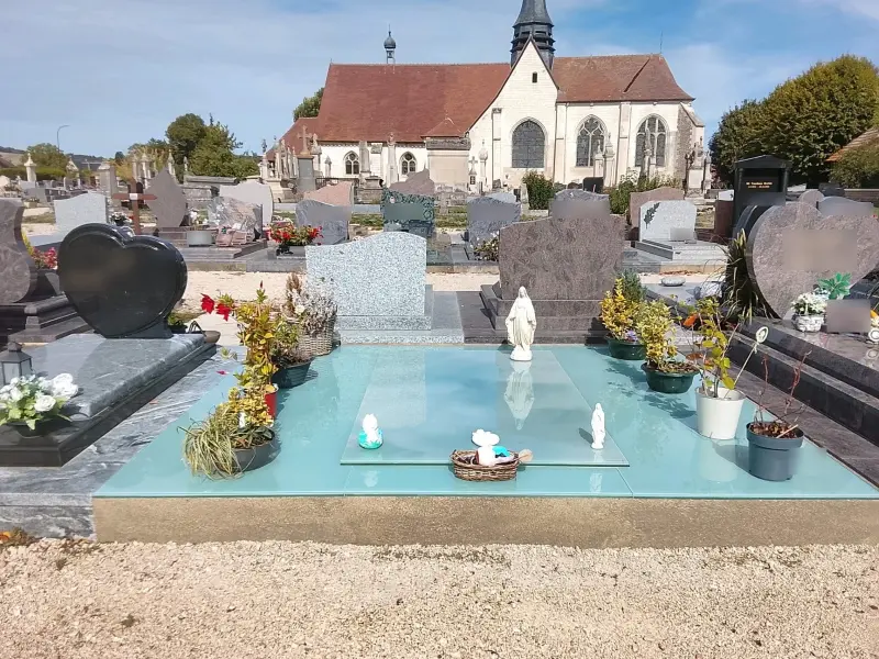Monument en verre turquoise posé dans un cimetière de village