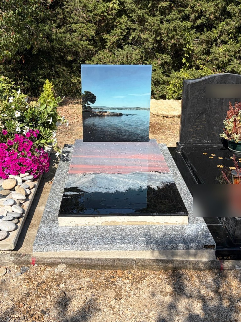 Monument en verre imprimé d'un paysage de bord de mer, posé dans un cimetière
